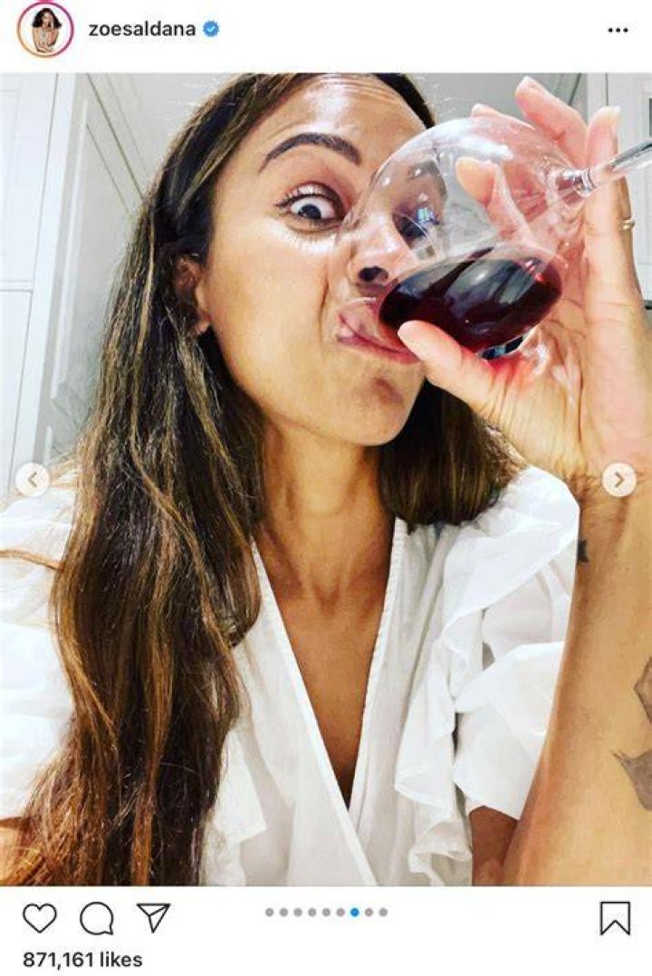 Zoe Saldana drinking wine while showing off a funny expression. | Photo: 